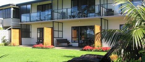 Ein modernes, zweistöckiges Haus mit Balkon, gepflegtem Rasen und einem Garten mit roten Blumen.