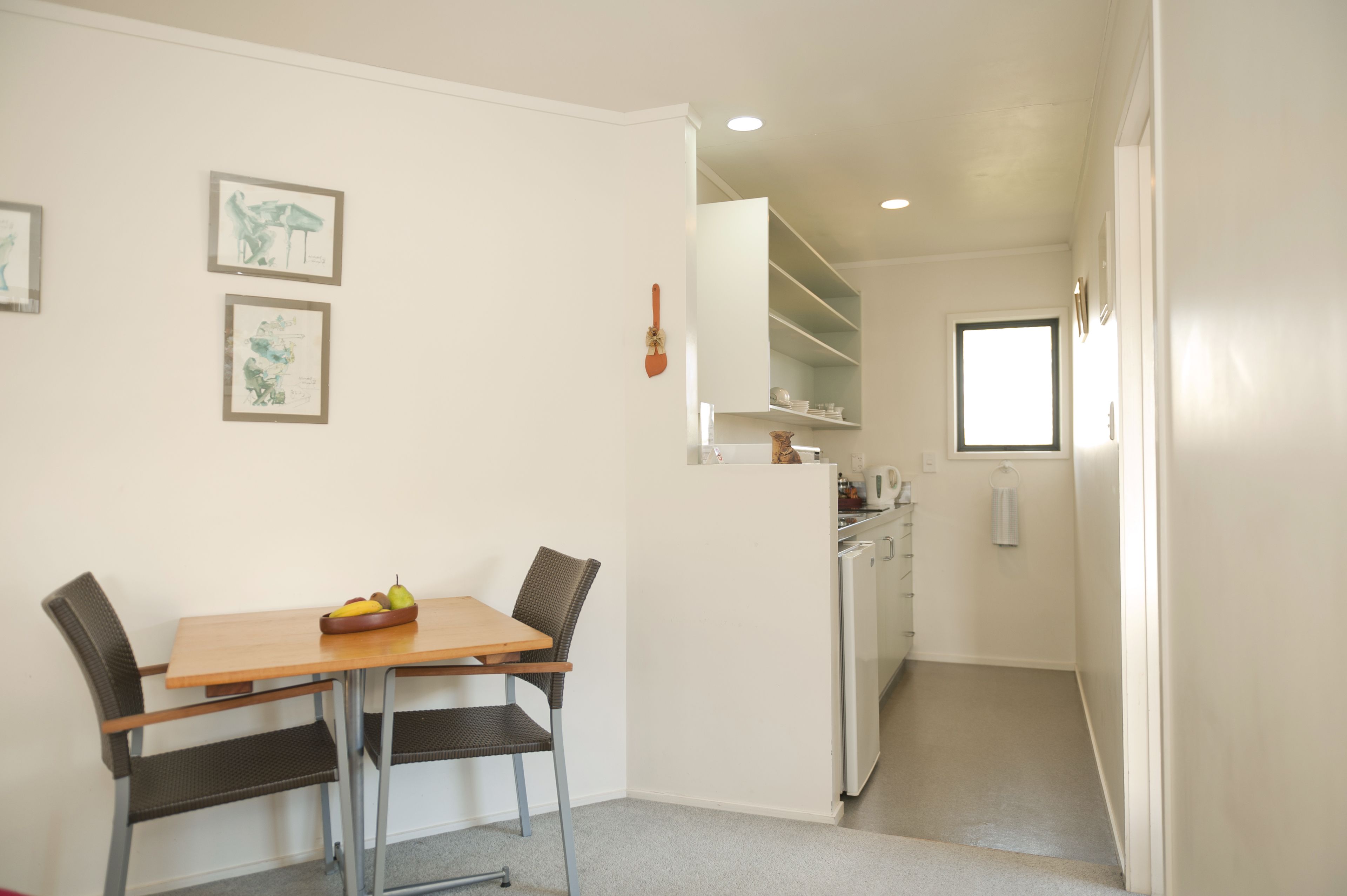 A compact kitchen with white cabinets, a refrigerator, and a window.