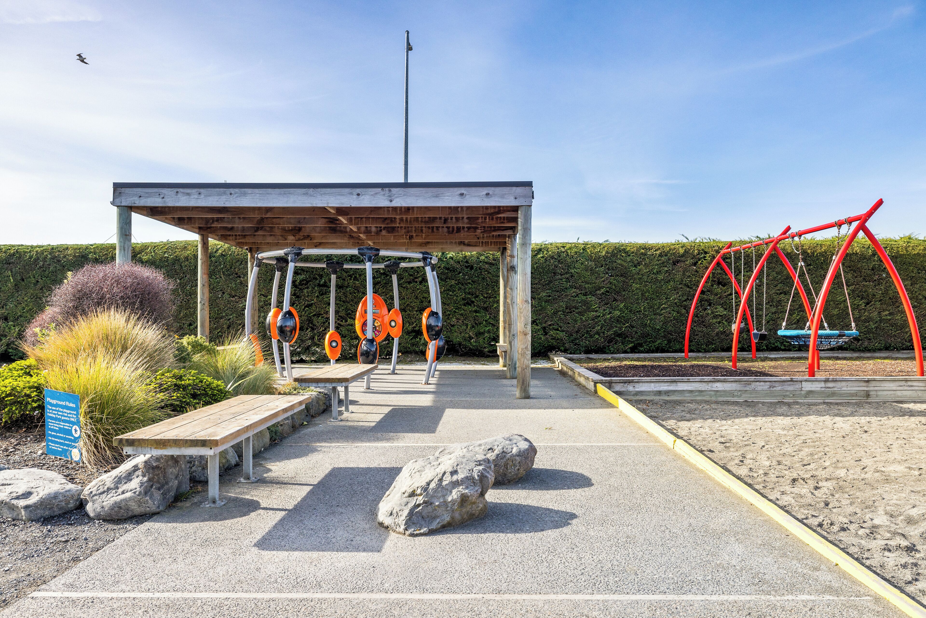 A playground with swings, a bench, and a covered area.