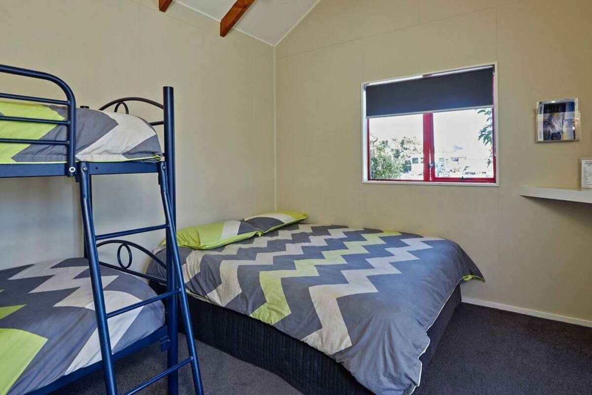 Une chambre avec des lits superposés, une fenêtre donnant sur un beau paysage et une petite étagère avec quelques objets.