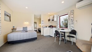 Een compacte hotelkamer met een bed, kitchenette en zithoek.