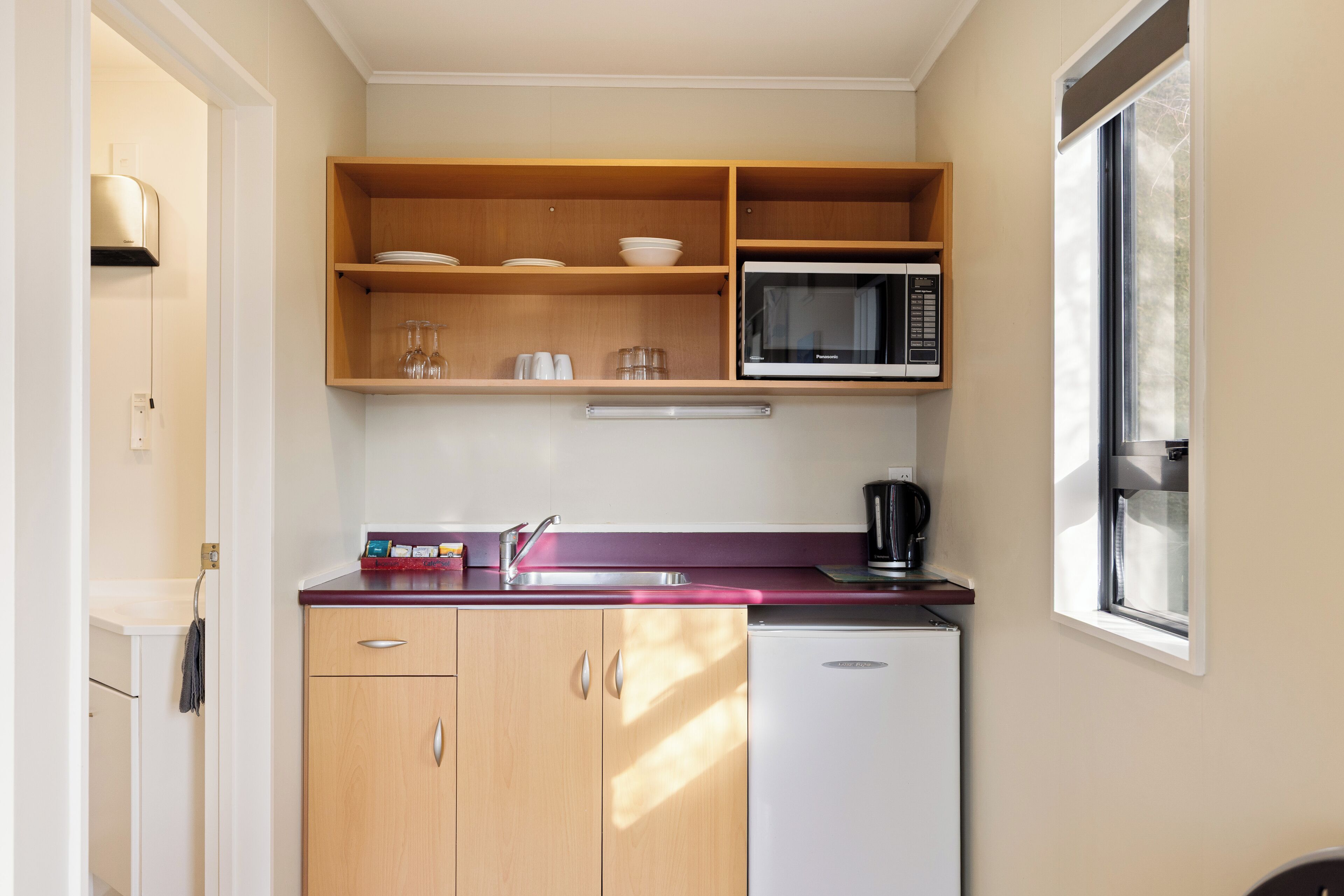 A compact kitchen with a microwave, a coffee maker, and a small refrigerator.