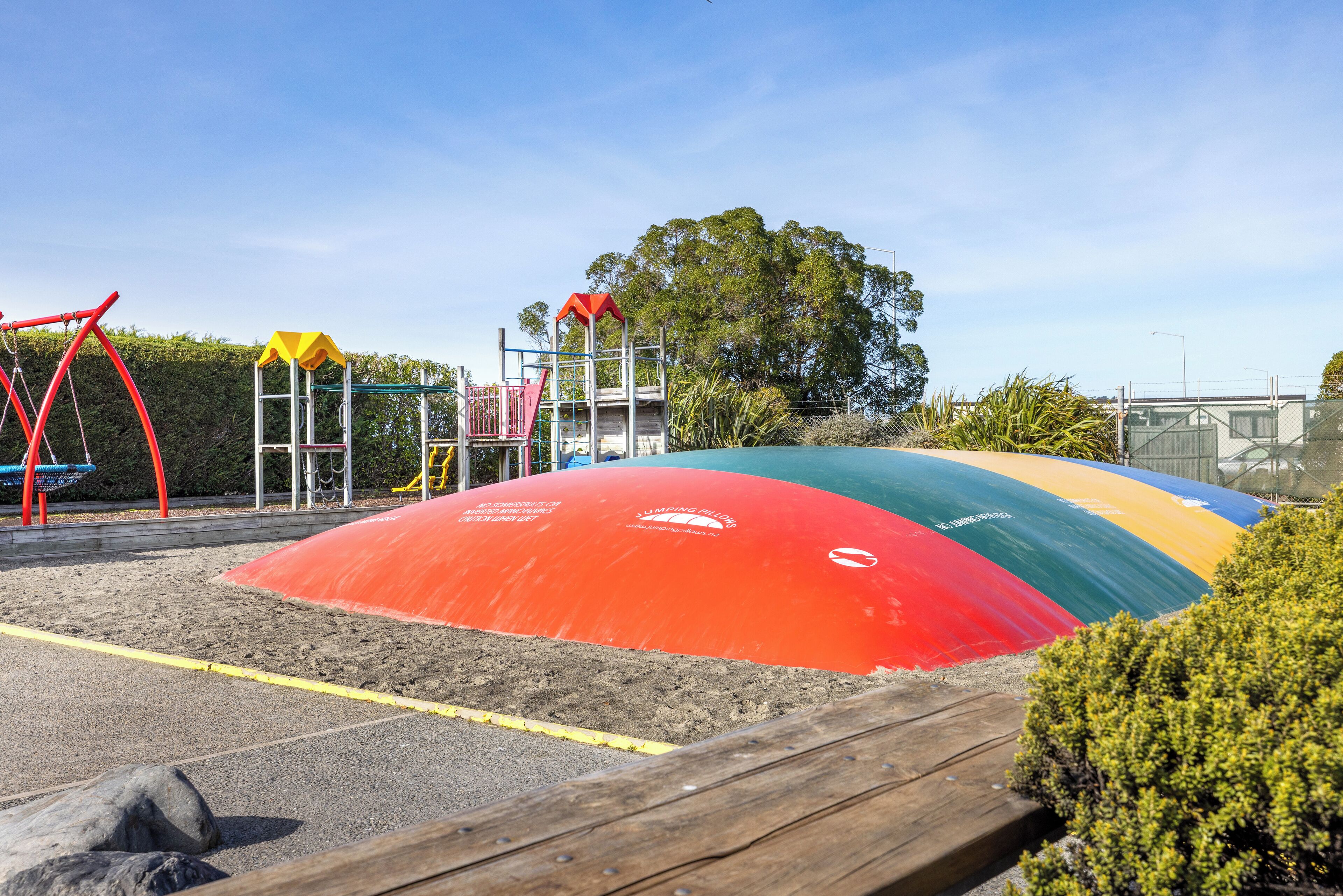 A playground with a sandpit, climbing structures, and a slide.