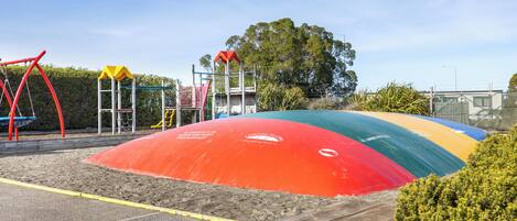 A playground with a sandpit, climbing structures, and a slide.