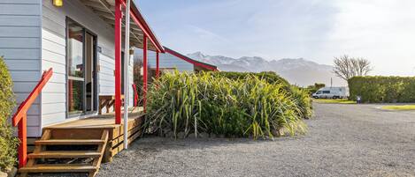 A building with a red porch and steps, a gravel driveway, and a mountain backdrop.