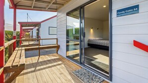Een chalet met een schuifdeur, een houten terras en een bordje met de tekst 'Family Cabin 54'.