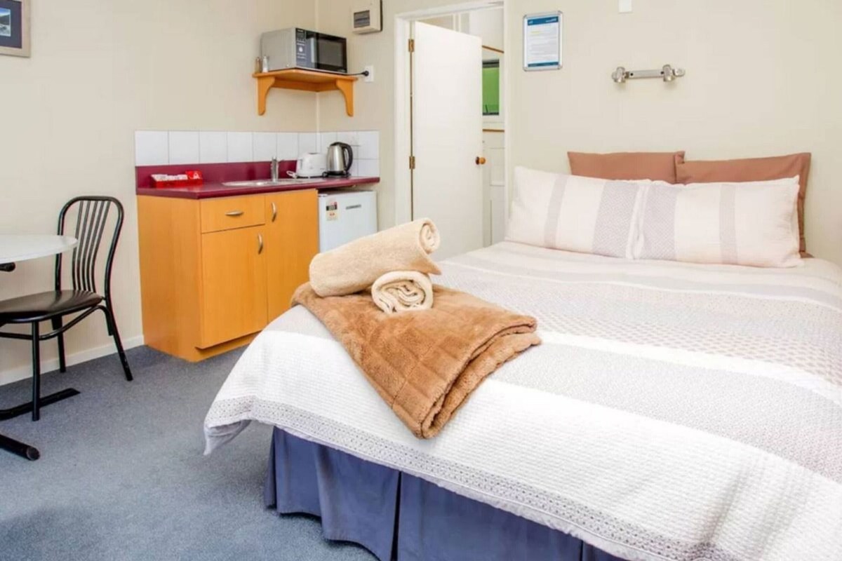 Hotelkamer met een bed, bureau, stoel, magnetron en een kleine kitchenette.