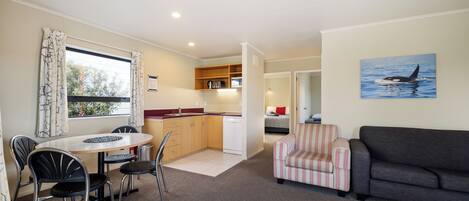 A compact living space with a dining area, kitchenette, and a sofa.