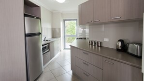 Een moderne keuken met roestvrijstalen apparatuur, lichte houten kastjes en een groot raam.