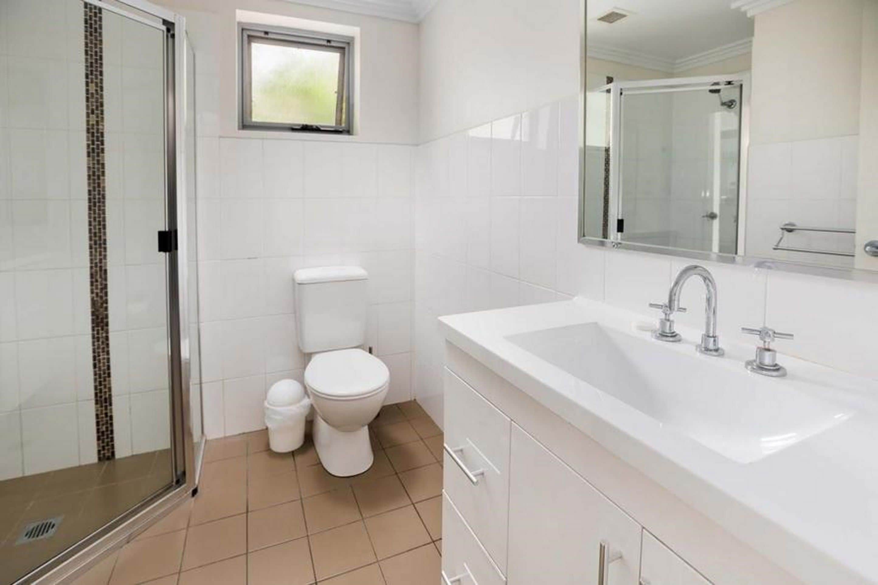 A modern bathroom with a walk-in shower, a toilet, and a sink with a mirror above it.