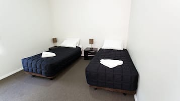 A twin room with two single beds, each with a bedside table and lamp, and a small drawer unit.