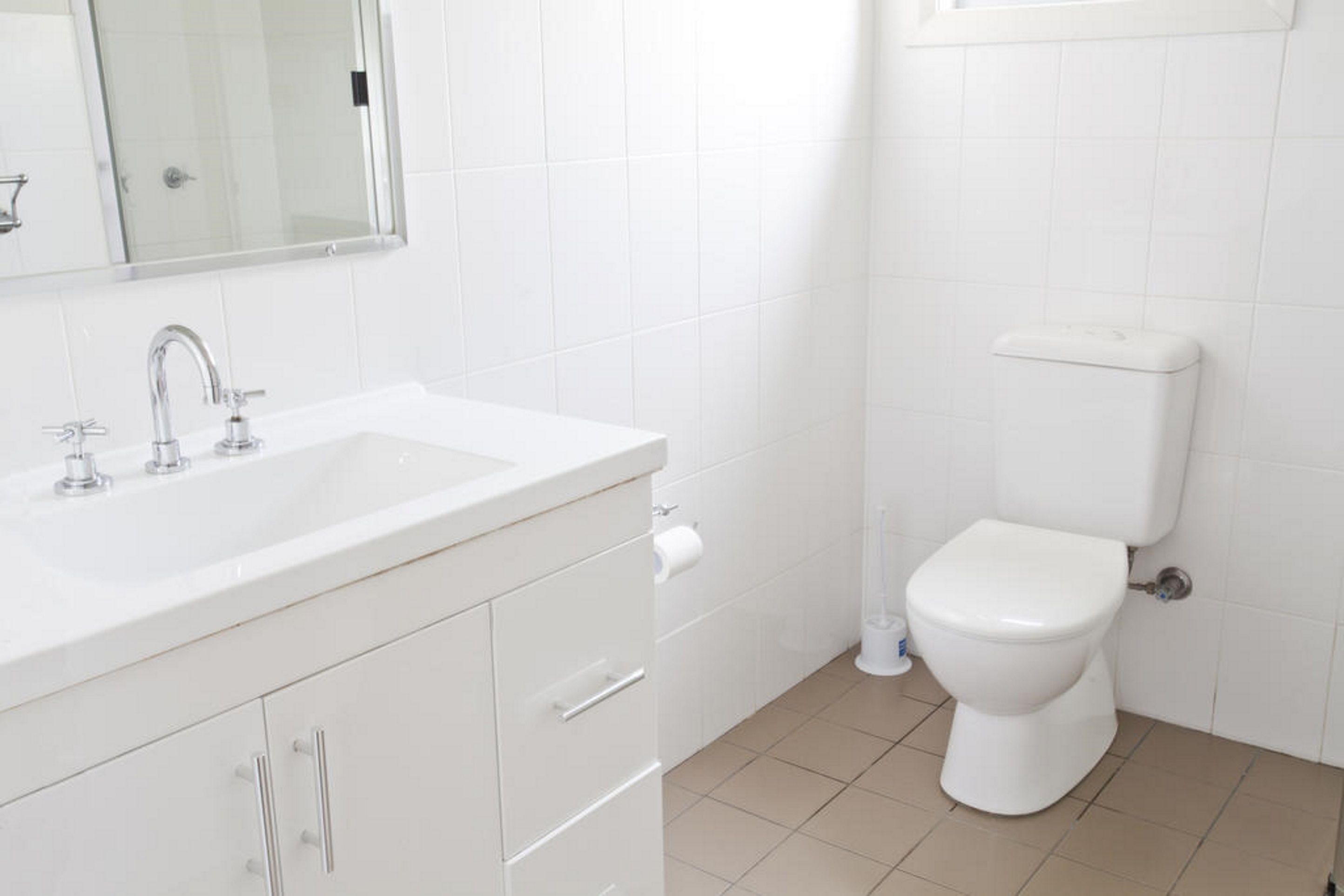 A bathroom with a white sink, mirror, and toilet.