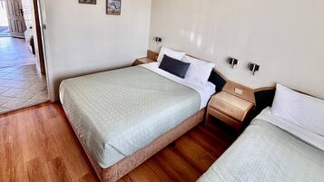 Une chambre d’hôtel avec deux lits, un plancher en bois et une porte donnant sur un couloir.