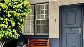 Un banco de madera frente a una casa con puerta y ventanas azules.
