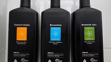 Three black bottles of Outback Essence personal care products: conditioner, shampoo, and shower gel. Each bottle is 400ml and marked as recyclable.