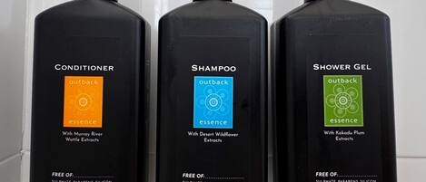 Tres botellas negras de productos de cuidado personal Outback Essence: acondicionador, champú y gel de ducha. Cada botella tiene 400ml y lleva la marca indicando que es reciclable.