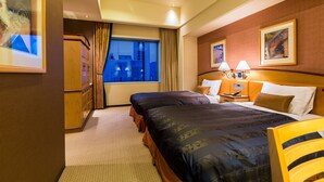 Hotelkamer met twee bedden, een groot raam, een houten garderobe en een nachtkastje met lampen.