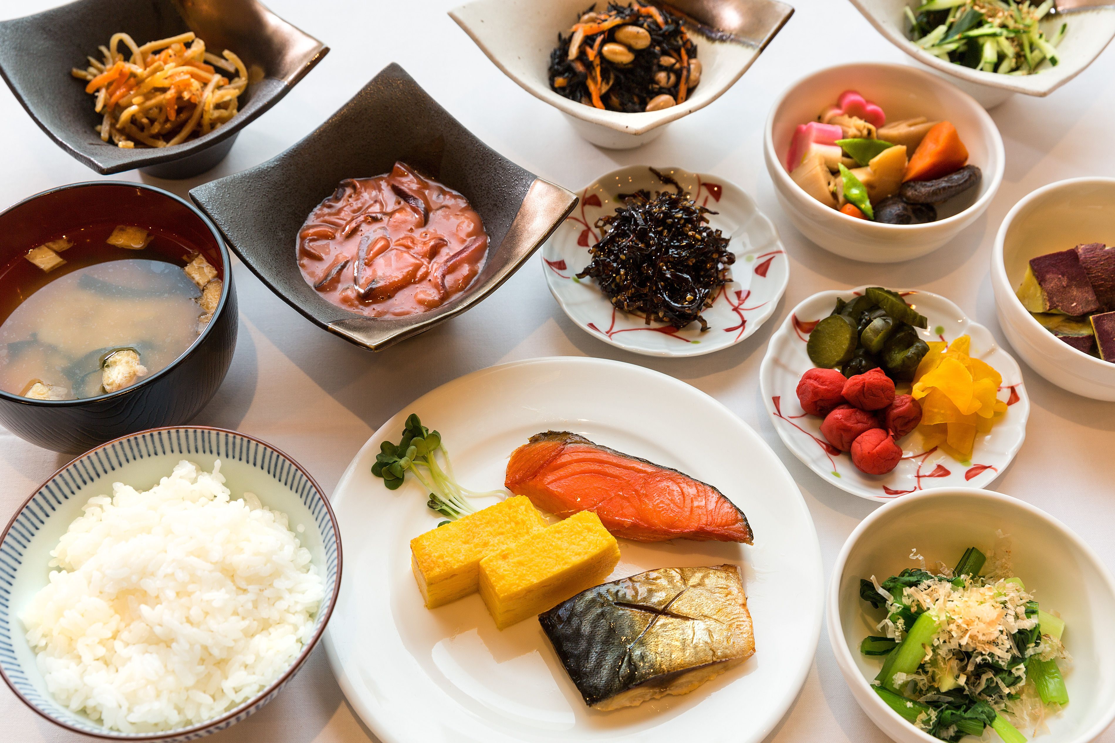 A variety of dishes including rice, salmon, and vegetables.
