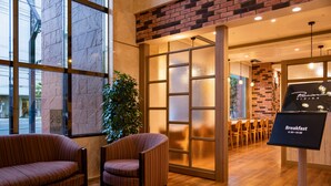 Een modern interieur met een zithoek, een plant en een bord met het woord 'ontbijt'.