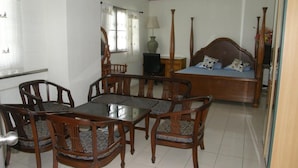 A room with a bed, a desk, and a dining table with chairs. - Anchana House by Zuzu (Pattaya)