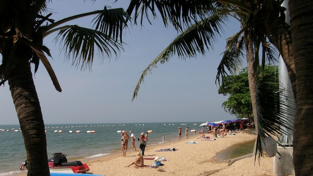A beach with palm trees, a boat, and people relaxing. - Anchana House by Zuzu (Pattaya)