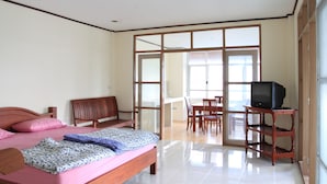 A bedroom with a bed, a wooden chair, a desk, and a television on a stand. - Anchana House by Zuzu (Pattaya)