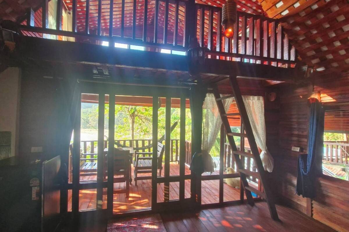 A wooden cabin with a balcony, a staircase, and a view of the outdoors.