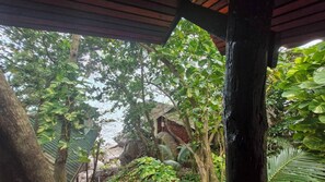 Un espacio al aire libre techado con vista a una casa rodeada de exuberante vegetación y árboles.