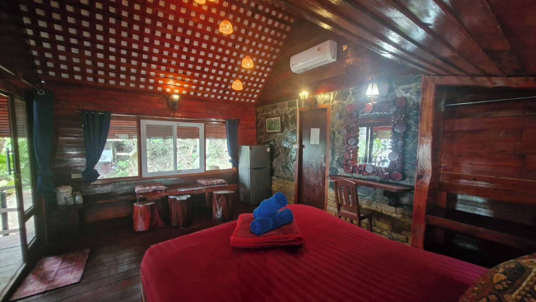 Une chambre confortable, aménagée dans le style d’un chalet, avec un grand lit, un bureau en bois et un mur en pierre.