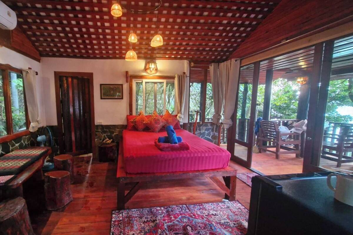 A cozy bedroom with a large bed, wooden furniture, and a view of the outdoors.