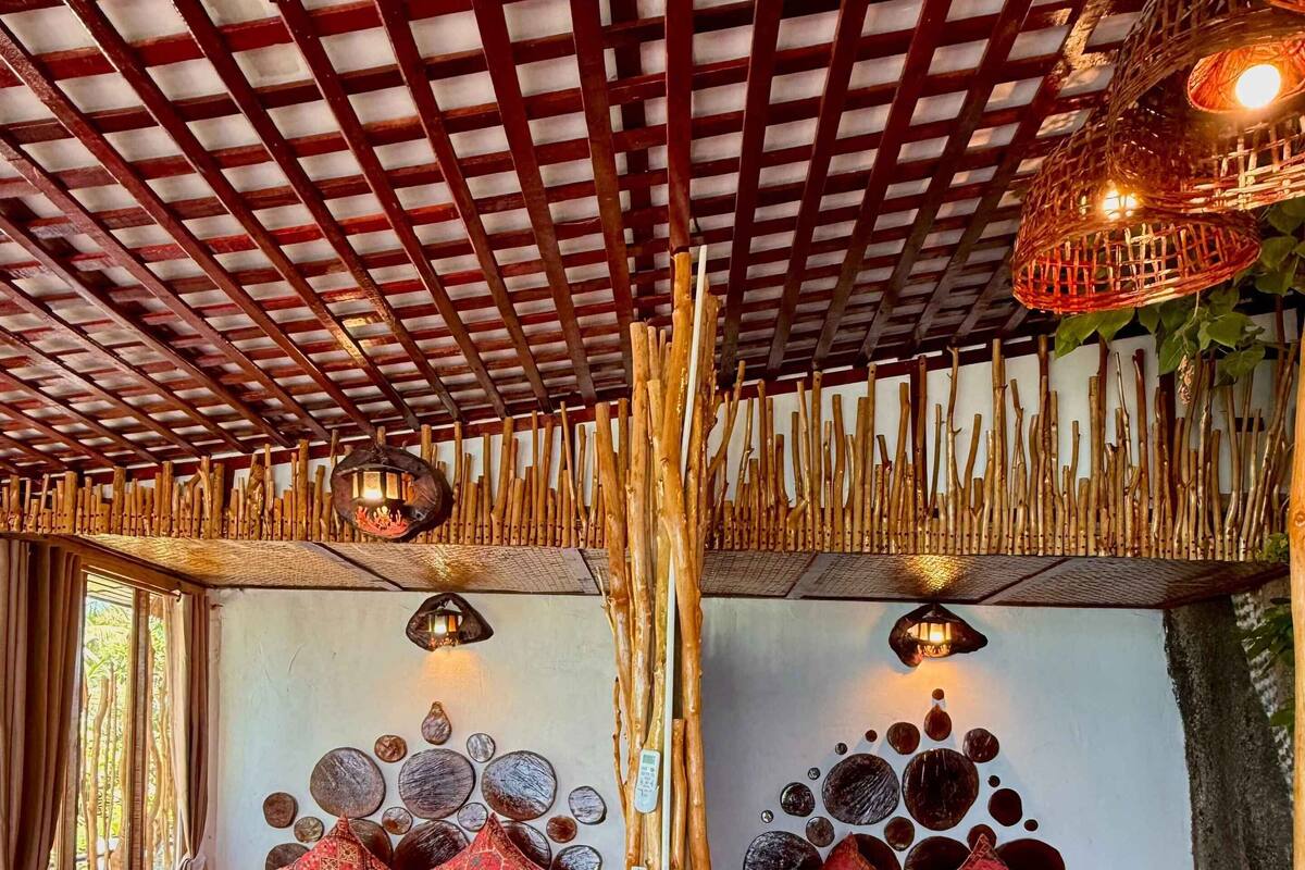 A room with two beds, wooden flooring, and a ceiling with a grid pattern.