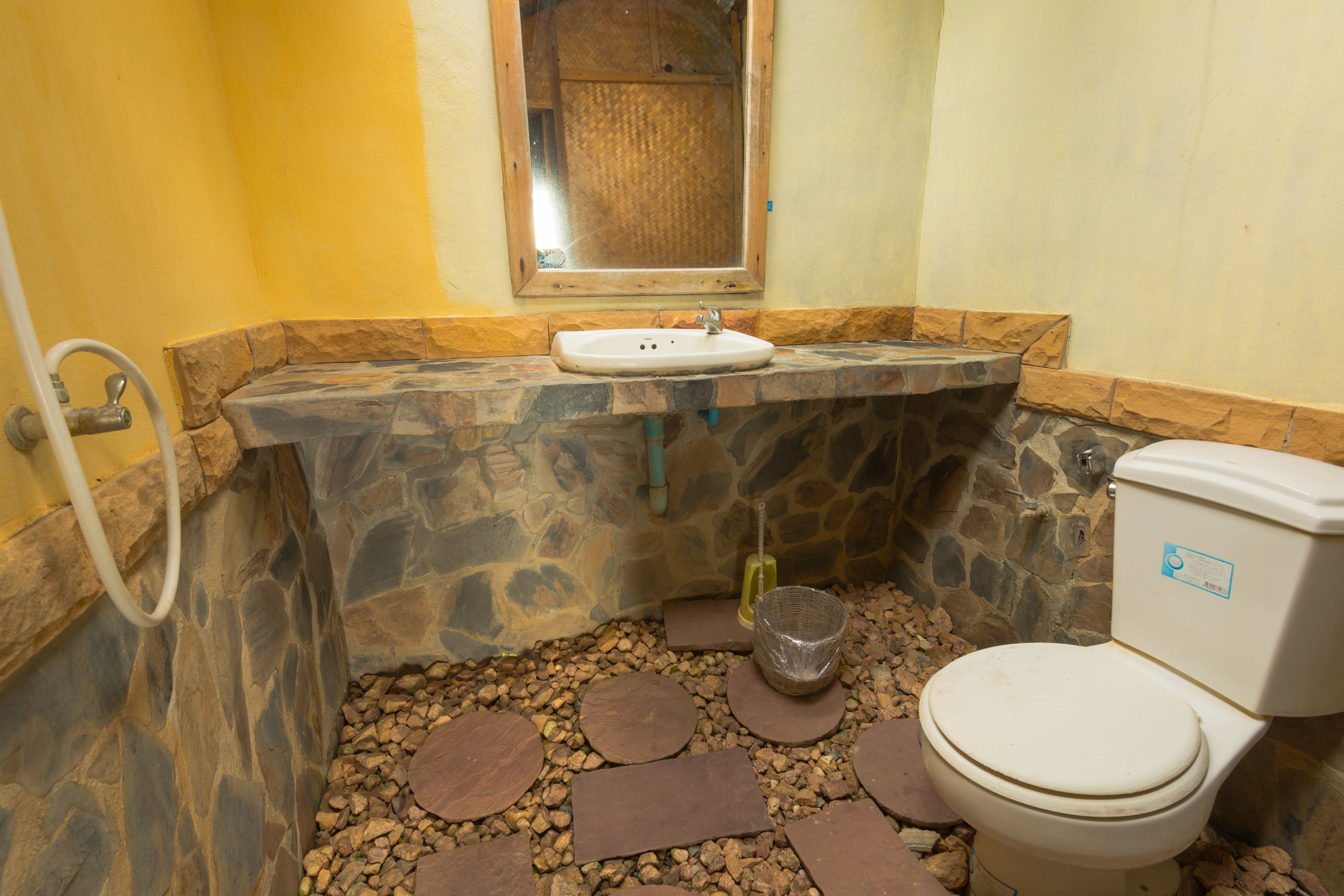 Un baño con lavabo de piedra, inodoro y espejo.