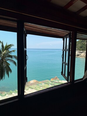 An open window with a view of the sea, a palm tree, and a rocky shoreline. - Mai Pen Rai Bungalows (Ko Pha-ngan)