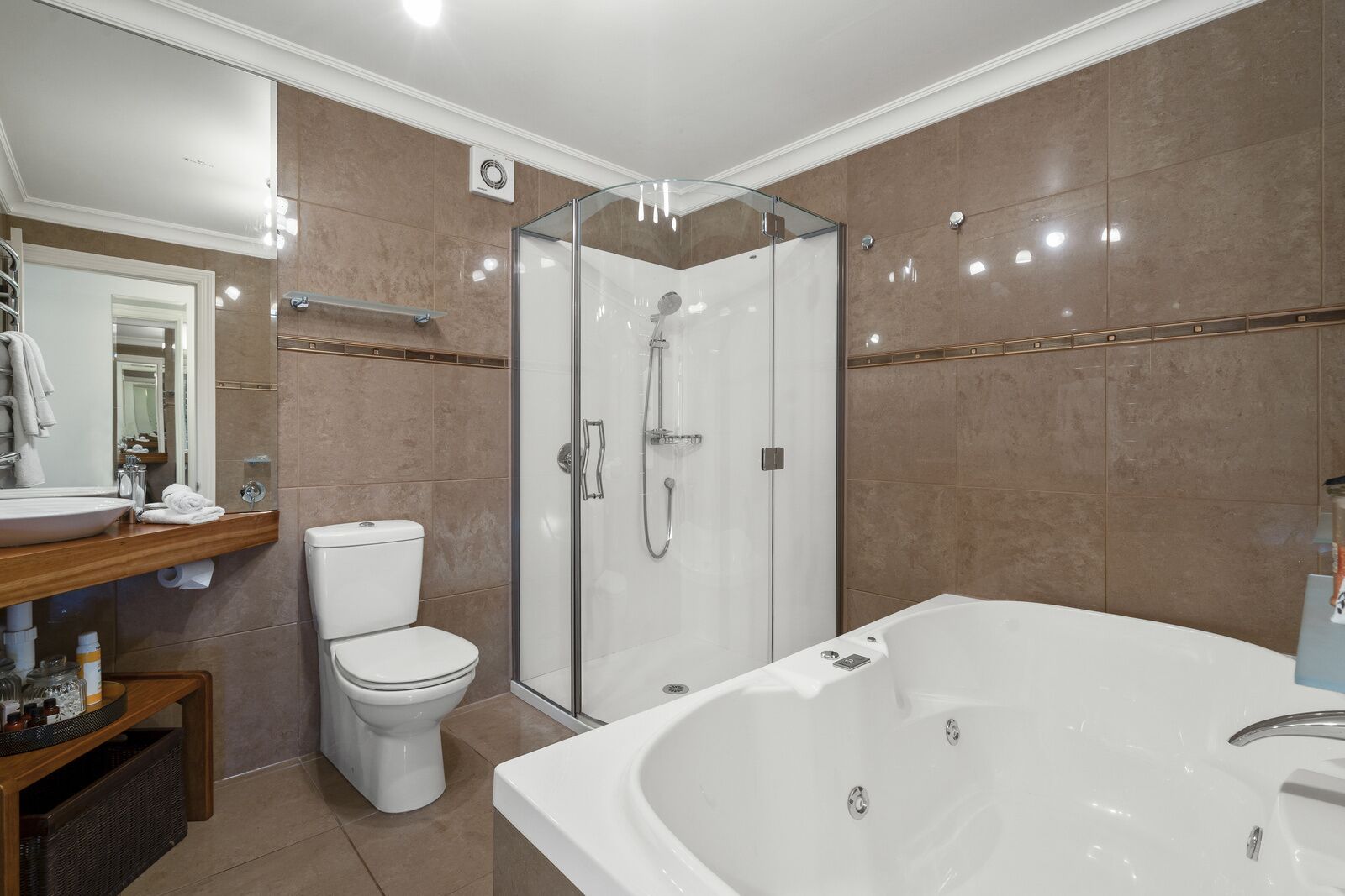 A modern bathroom with a glass-enclosed shower, a large bathtub, and a toilet.
