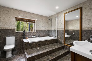 A modern bathroom with a bathtub, a toilet, and a sink. - Sanctuary Palms (Paihia)