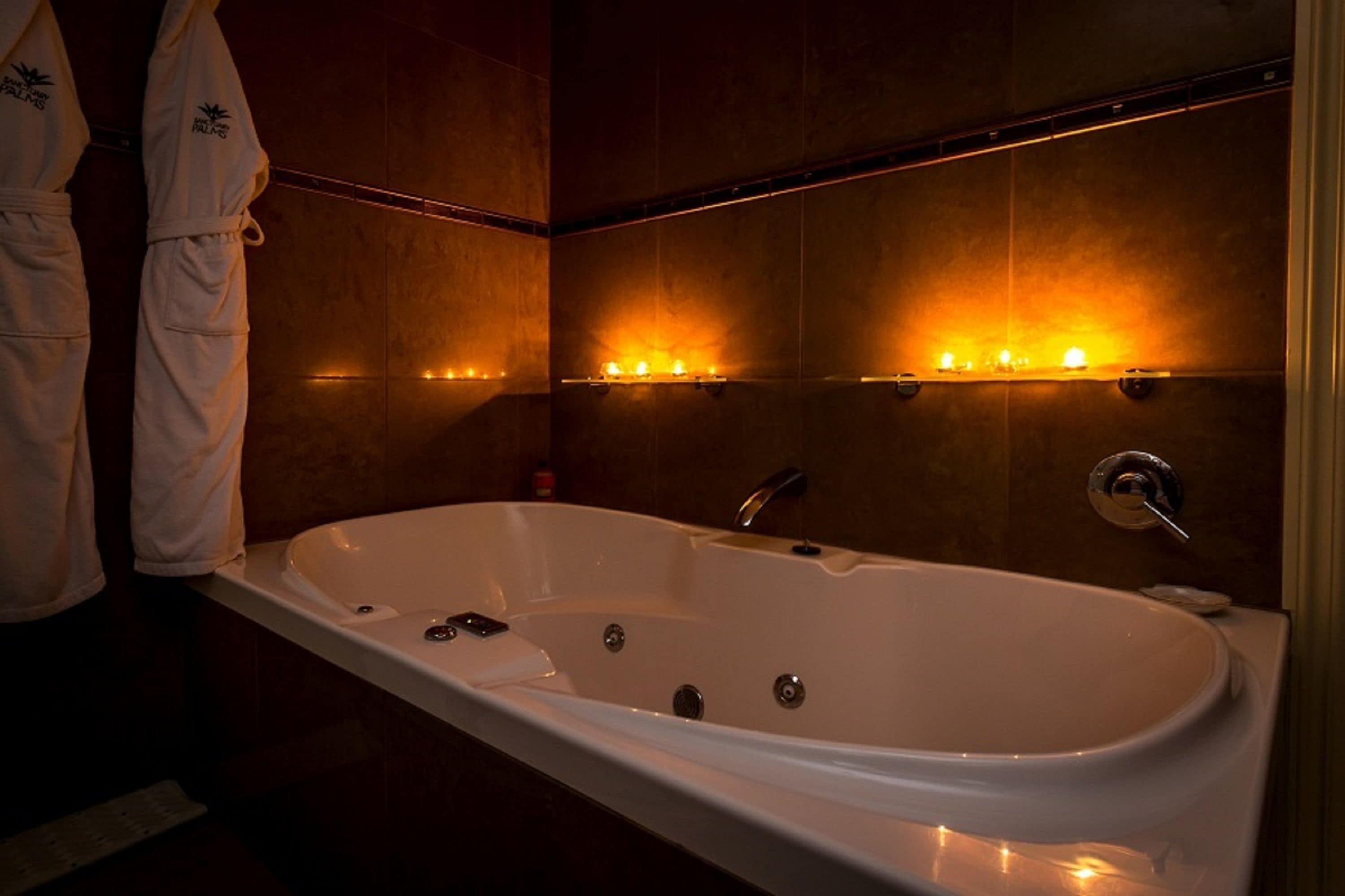 A modern bathroom with a large bathtub, wall-mounted lights, and a towel rack.