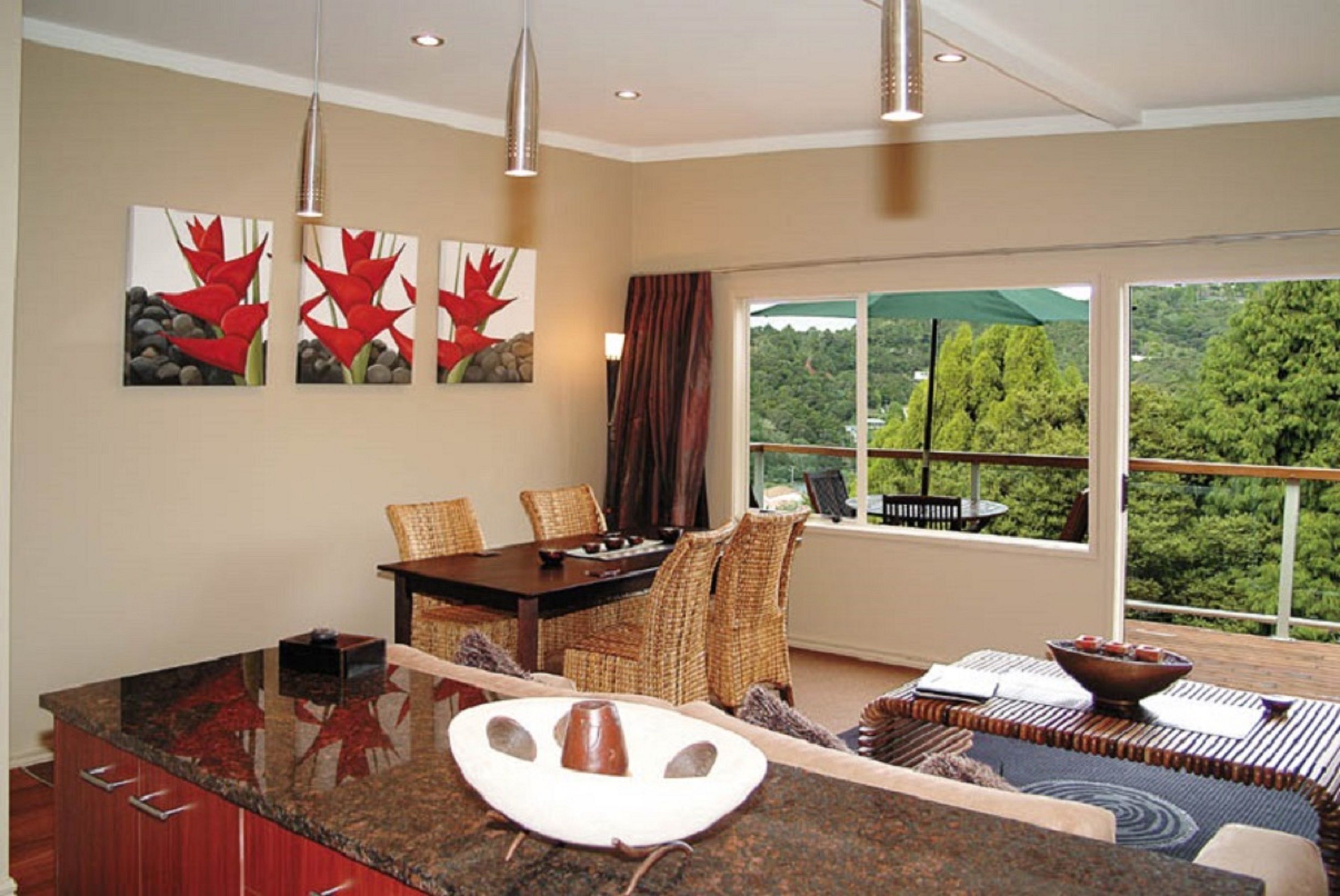 A dining area with a large window, a dining table with chairs, and a view of greenery outside.