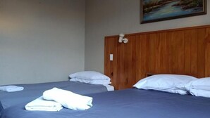 Quarto de hotel com duas camas, cabeceira de madeira e um quadro de uma paisagem de montanha na parede.