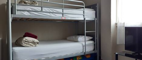 Una cama litera con un televisor sobre un soporte a la derecha.