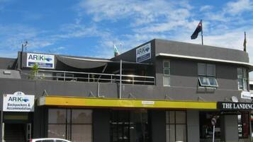 Un edificio con letreros que indican 'ARIK Backpackers & Accommodation' y 'The Landing Cafe'.