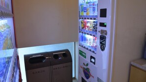 A vending machine with various drink options and a trash bin. - Swanky Hotel Otomo (Sapporo)