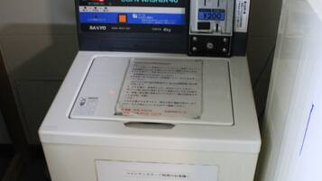 A coin-operated washing machine with a digital display, a water inlet, and a power outlet.