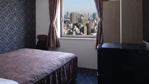 A hotel room with a bed, a dresser, a window with curtains, and a cityscape view. - Swanky Hotel Otomo (Sapporo)