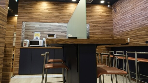 A restaurant interior with a counter, seating, and a wooden wall design. - Swanky Hotel Otomo (Sapporo)