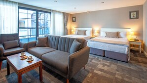 A hotel room with a sofa, two beds, a small table with cups, and a view of the outside. - Aston Hotel Taksim (Istanbul)