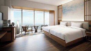 Et moderne hotelværelse med en stor seng, et skrivebord, en stol og udsigt over byen.