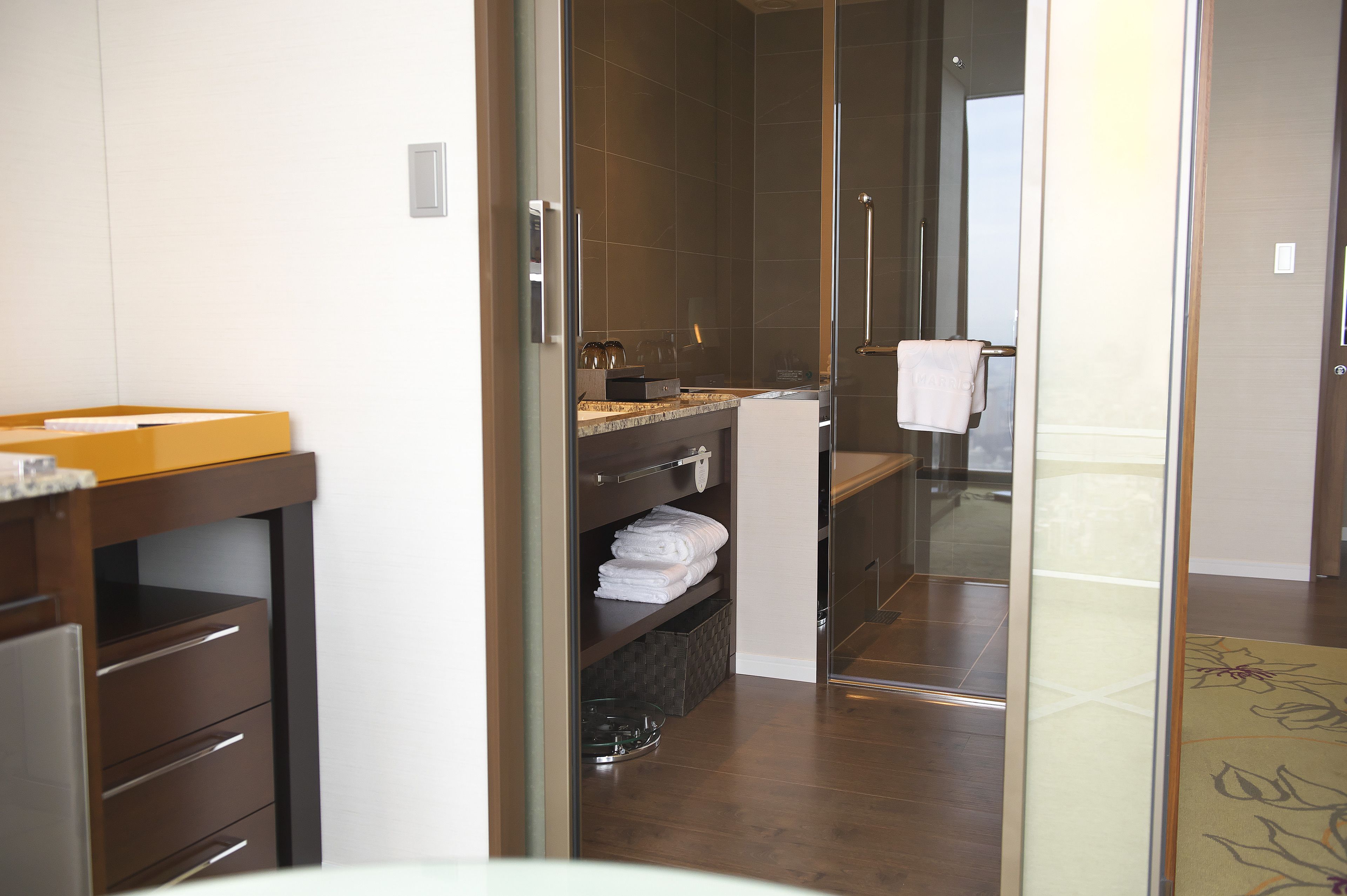 A modern bathroom with a glass shower enclosure, a wooden vanity, and neatly folded towels.