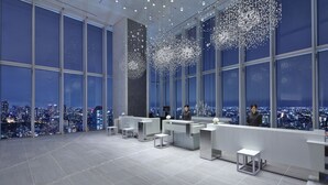 En moderne hotellobby med store vinduer, en receptionsdisk og udsigt over byen.