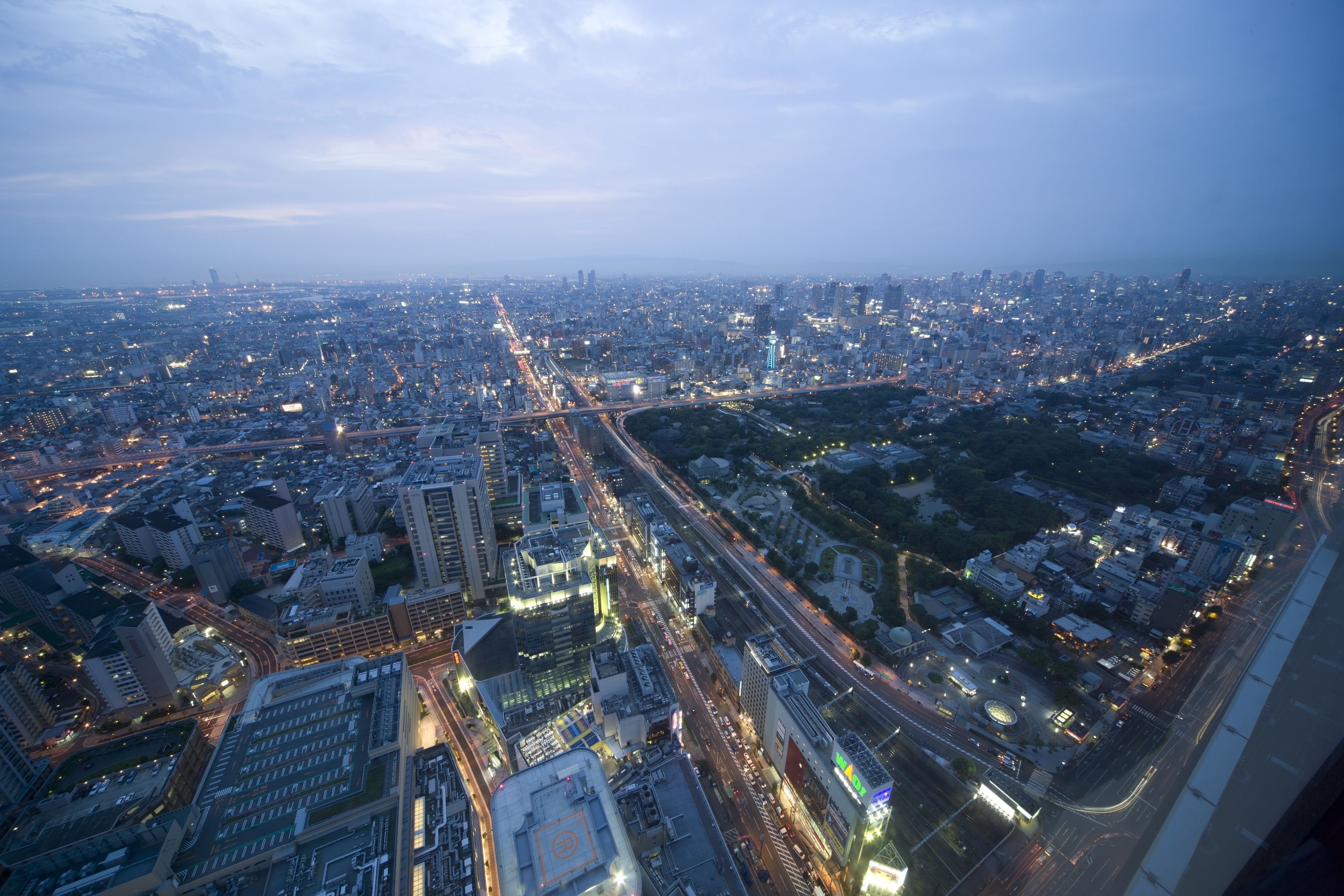 A cityscape at dusk with illuminated buildings and a highway.