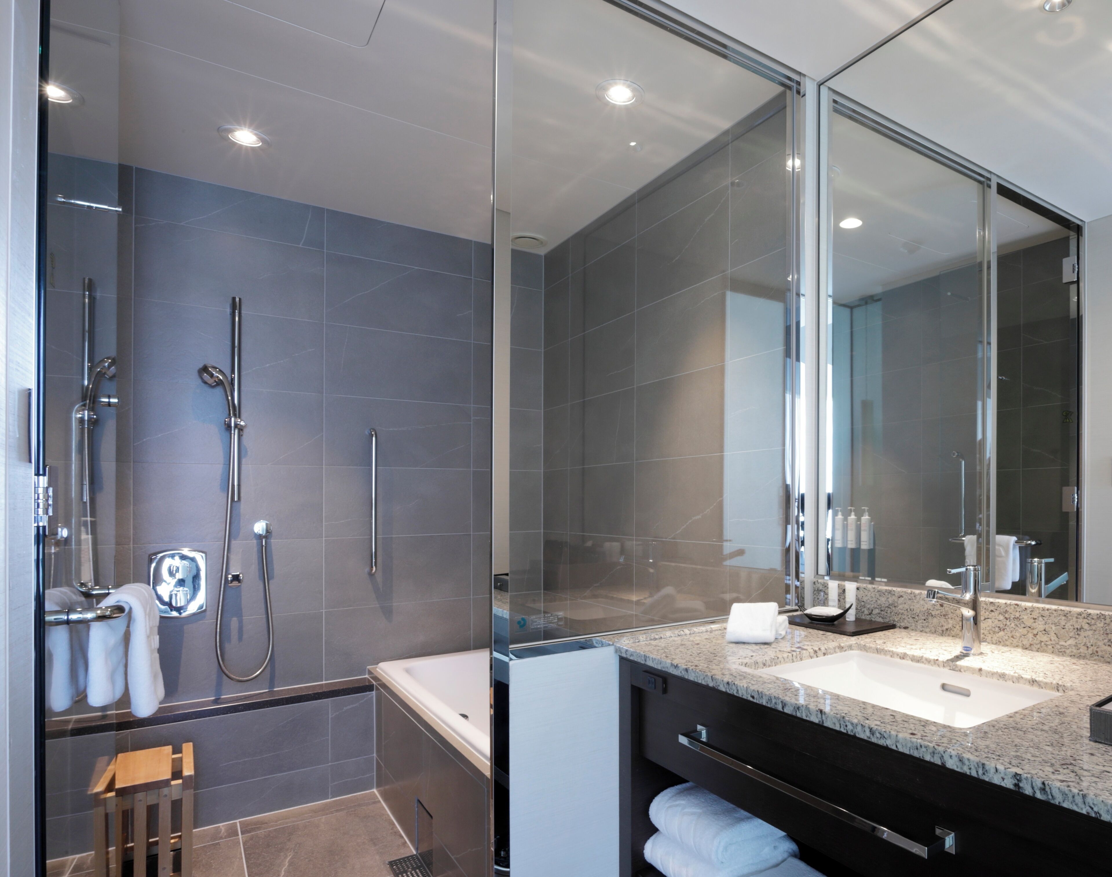 A modern bathroom with a glass shower enclosure, a bathtub, and a vanity with a sink and mirror.